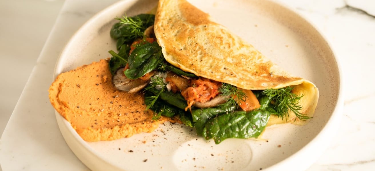  A plate containing an omelette filled with herbs accompanied with bread.